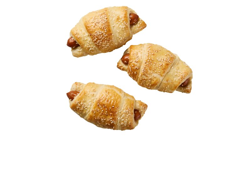 Trois croissants salés avec saucisse et graines de sésame sur fond noir.
