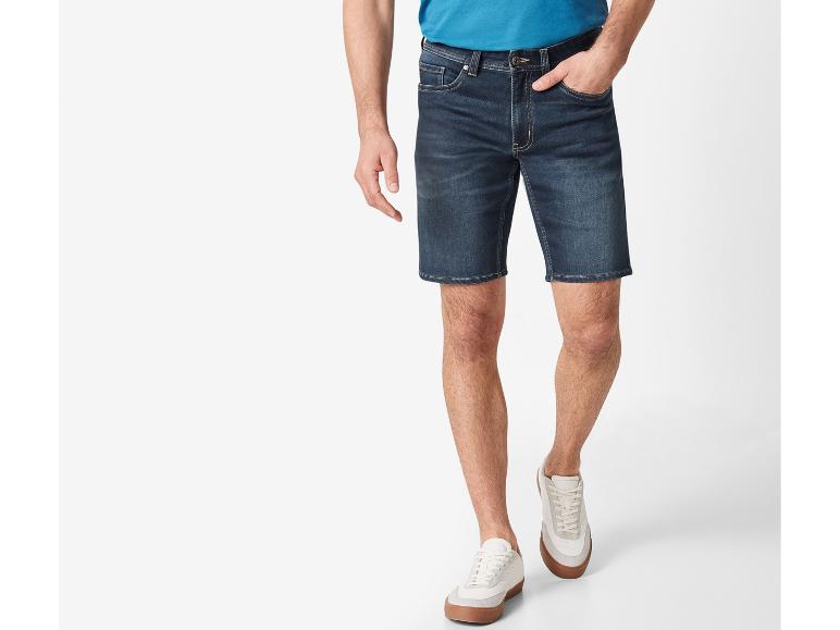Un homme porte un short en jean et des baskets blanches.