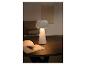 Lampe de table blanche élégante en forme de champignon, éclairant un livre sur une table basse.