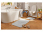 Salle de bain avec baignoire, toilettes et deux tapis de bain.