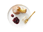 Gâteau saupoudré de sucre glace, compote de cerises et crème fouettée sur une assiette blanche.