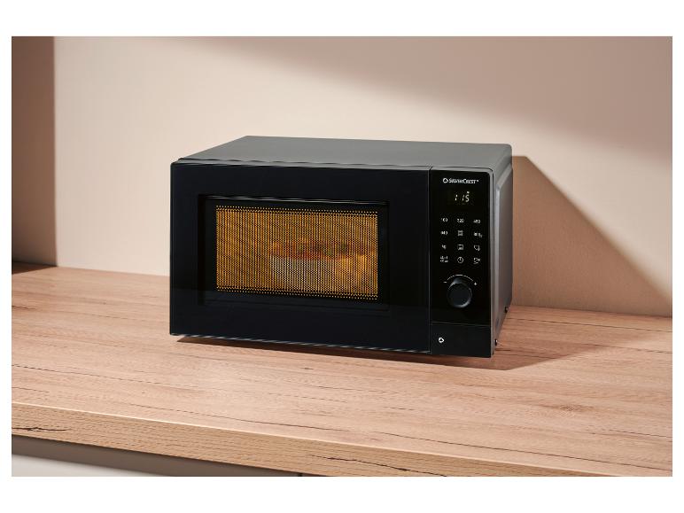 Micro-ondes noir avec affichage numérique et bouton sur un comptoir en bois.