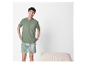 Homme souriant portant un pyjama vert clair à manches courtes et un short rayé.
