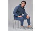 Homme en survêtement bleu marine et baskets grises, assis sur un tabouret.