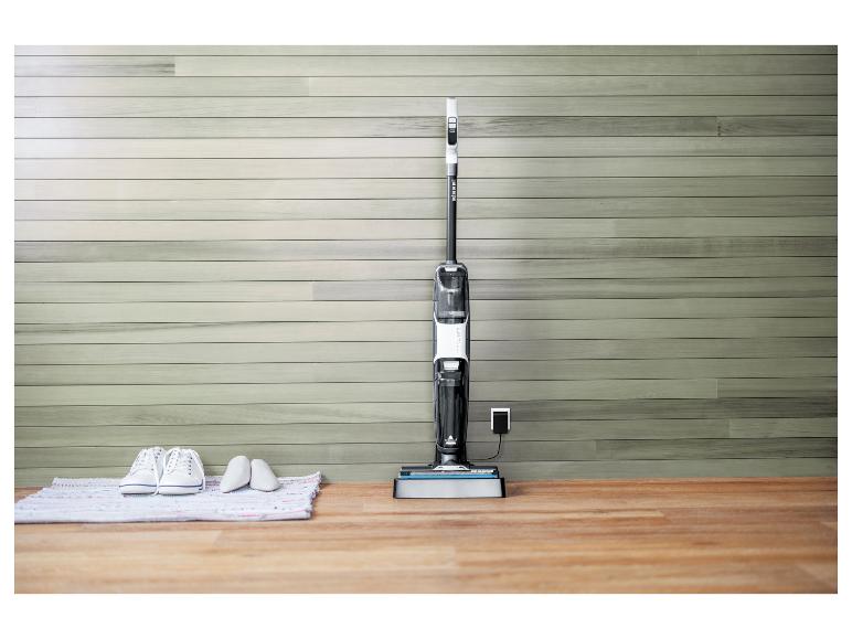 Aspirateur balai Bissell CrossWave HF3 en charge sur un sol en bois.