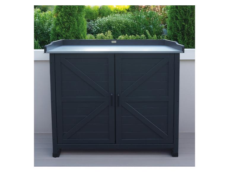 Armoire d'extérieur gris foncé avec deux portes et un plan de travail clair, entourée de plantes vertes.