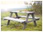 Table de pique-nique grise pour enfants avec coussins et nourriture jouet sur l'herbe.