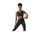 Femme en brassière de sport noire et legging tenant un ballon d'exercice gris