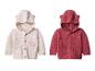Deux cardigans tricotés pour bébé, un crème avec broderie florale et un rouge, tous deux avec capuche à oreilles.