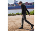 Un homme marche sur la plage avec des bottes noires et un jean foncé.