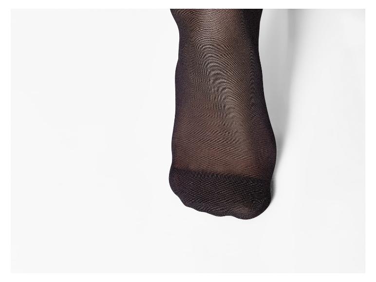 Pied avec des collants ou des bas noirs sur fond blanc