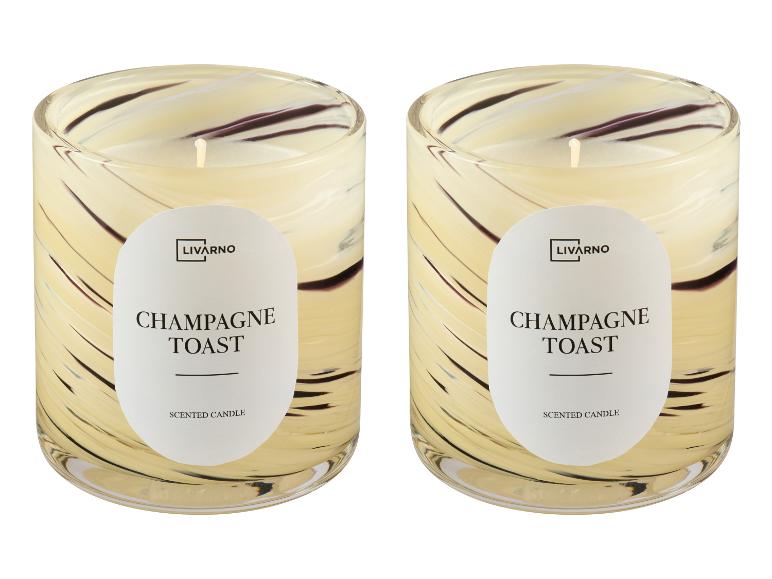 Deux bougies parfumées 'Champagne Toast' dans des récipients en verre à motif spiralé.