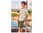 Un homme avec un t-shirt clair et un short vert à côté d'une piscine.