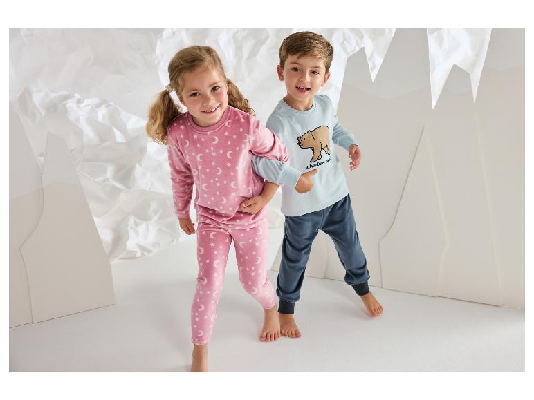 Enfants souriants en pyjamas confortables, avec des motifs d'étoiles et d'ours.