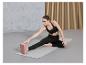 Une femme fait un étirement sur un tapis de yoga avec un bloc de yoga.