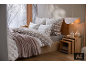 Chambre d'hiver chaleureuse avec literie à motifs, plaid doux et tables de chevet en bois.