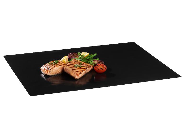 Saumon grillé avec des légumes sur un tapis de cuisson noir.