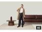 Femme en manteau beige et pantalon large foncé, debout dans un salon.