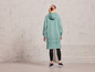 Une femme portant un sweat-shirt à capuche vert avec l'inscription 'Jette Sport', un legging et des baskets.