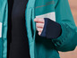 Une veste bleu-vert avec une bande blanche et une manche noire.