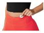 Haut noir et short de sport orange vif; une femme range un objet dans la poche du short.