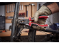 Mains gantées serrant une pièce de vélo avec une pince, panneau d'outils en arrière-plan.