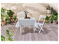 Table blanche avec deux chaises et une nappe blanche sur une terrasse en bois.
