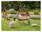 Jardin avec un fauteuil suspendu marron, une chaise Adirondack en bois et une table d'appoint.