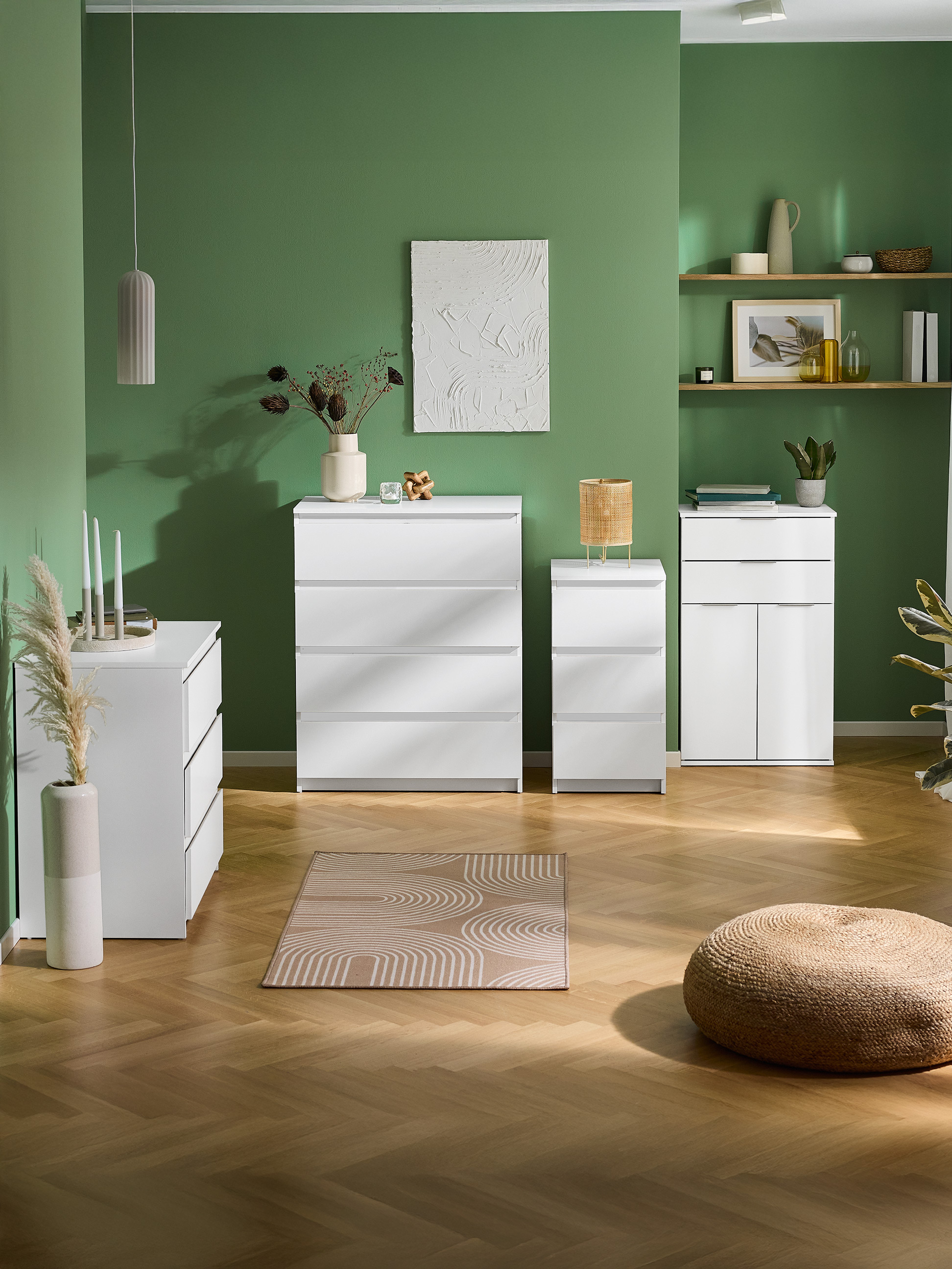 Commodes et armoires blanches dans une pièce verte avec parquet et tapis.