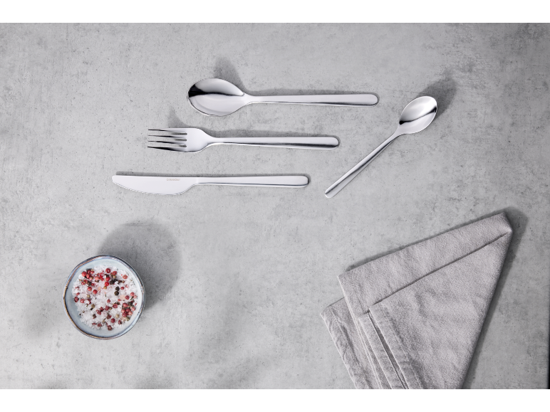 Un ensemble de couverts modernes en acier inoxydable sur fond gris.