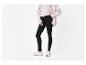 Femme en jean skinny noir, haut blanc et surchemise rose pâle, portant des baskets blanches.