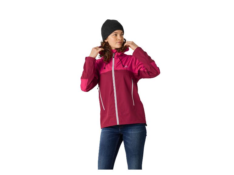 Femme portant une veste à capuche rose et bordeaux et un bonnet gris foncé, debout et regardant vers la droite.