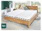 Lit en bois avec deux matelas blancs et oreillers dans une chambre avec vue sur le jardin.