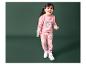 Une fille portant un pull rose avec un renne et un pantalon assorti.