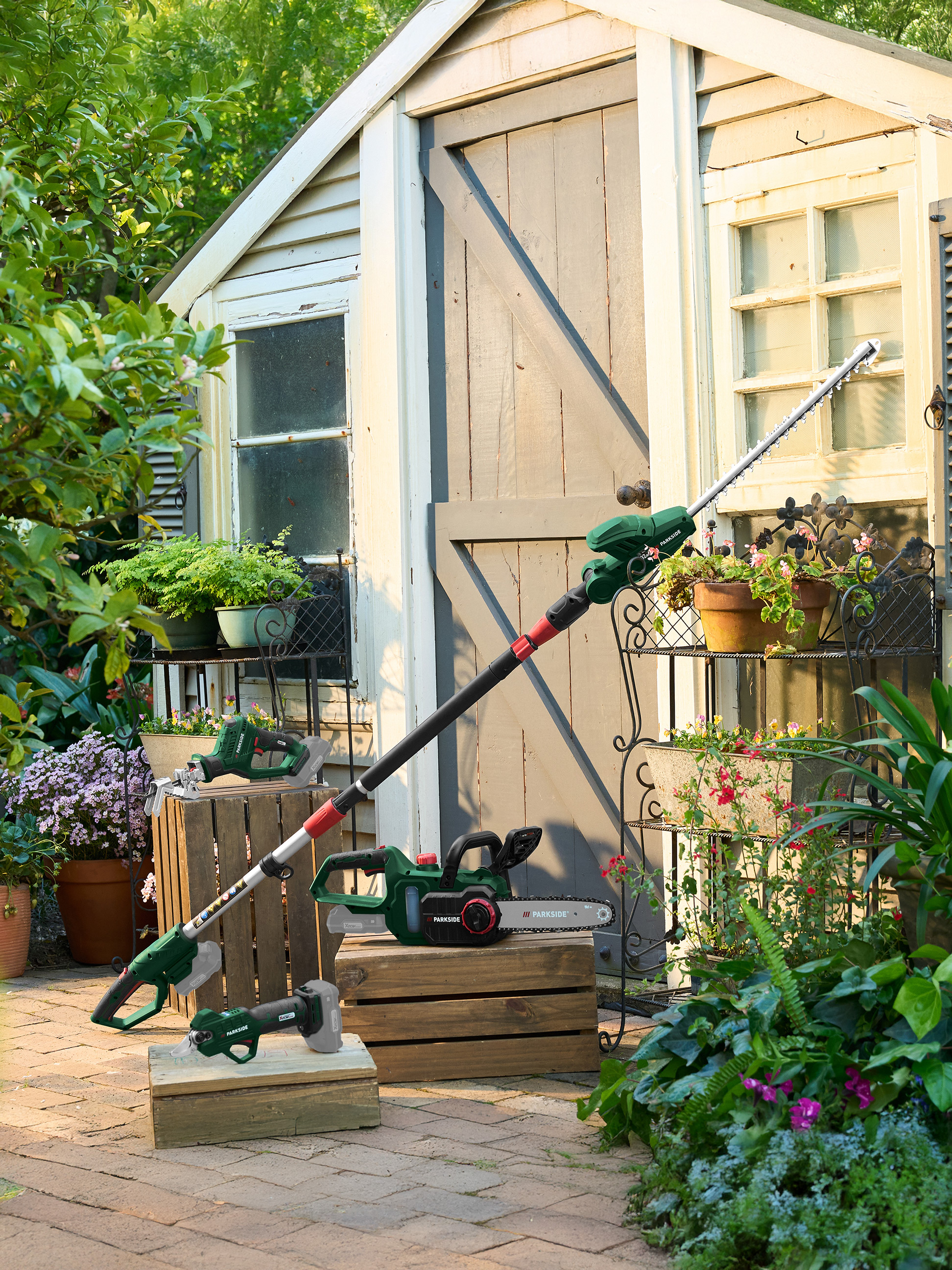 Outils de jardin Parkside: taille-haie télescopique, tronçonneuse et élagueur dans un jardin.