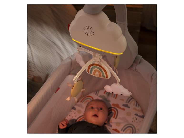 Bébé dans un berceau avec un mobile arc-en-ciel et nuages.