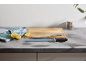 Scène de cuisine avec planche à découper en bois, couteau, fusil à aiguiser, citrons et torchon vert.