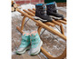 Des bottes de neige noires et bleu clair sur un traîneau en bois.