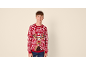 Garçon souriant portant un pull de Noël rouge avec un renne.