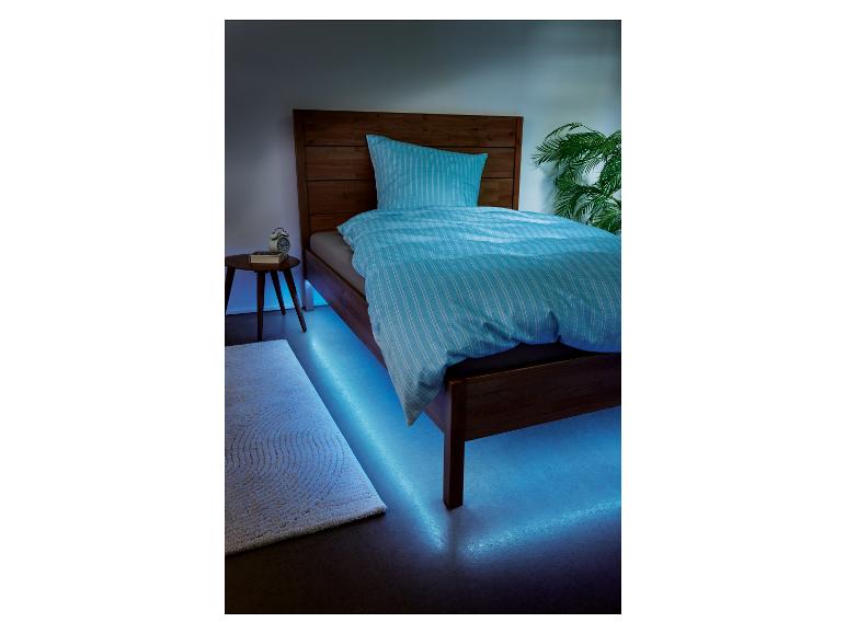 Un lit avec des draps bleus et un éclairage LED.