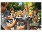 Famille prenant le petit-déjeuner en extérieur avec table et chaises de jardin.