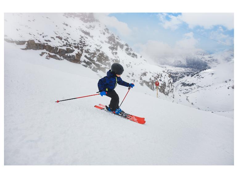 Enfant en tenue de ski bleue et casque noir skiant sur une pente de montagne enneigée.