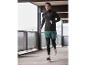 Un homme en tenue de sport noire court dans un parking.