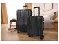 Deux valises noires, une grande et une petite, dans une pièce lumineuse avec un lit.