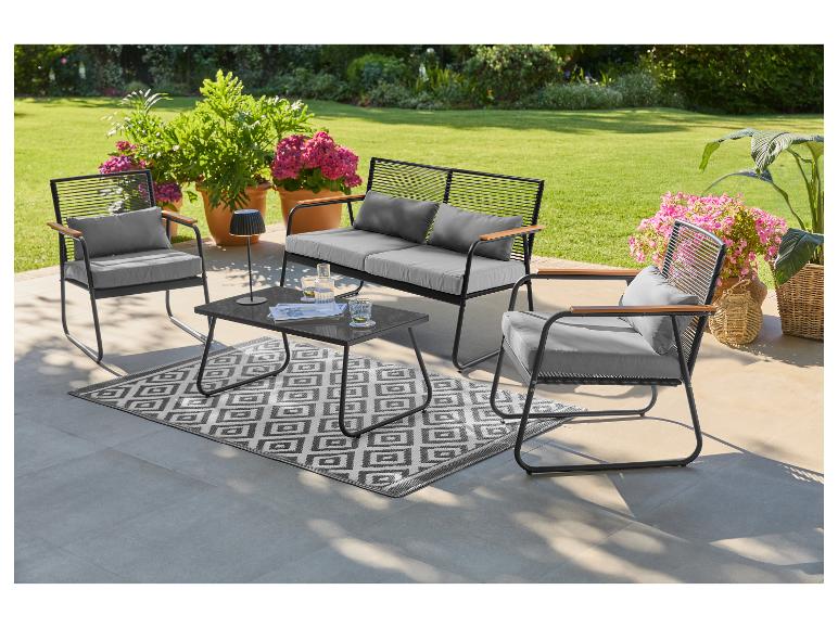 Ensemble de mobilier d'extérieur avec canapé, deux fauteuils, table basse et tapis sur une terrasse.