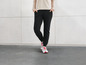 Pantalon de survêtement noir et baskets blanches avec lacets rouges.