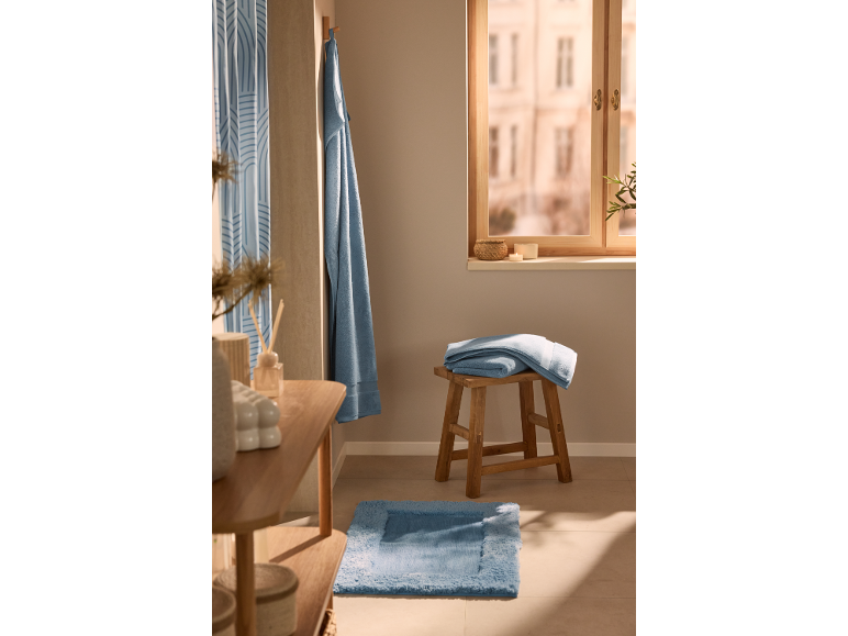 Serviettes bleues et tapis de bain dans une salle de bain chaleureuse.