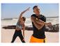 Homme et femme s'étirant en vêtements de sport sur la plage.