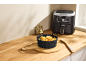Un moule en silicone noir pour friteuse sans huile rempli de frites sur une planche en bois