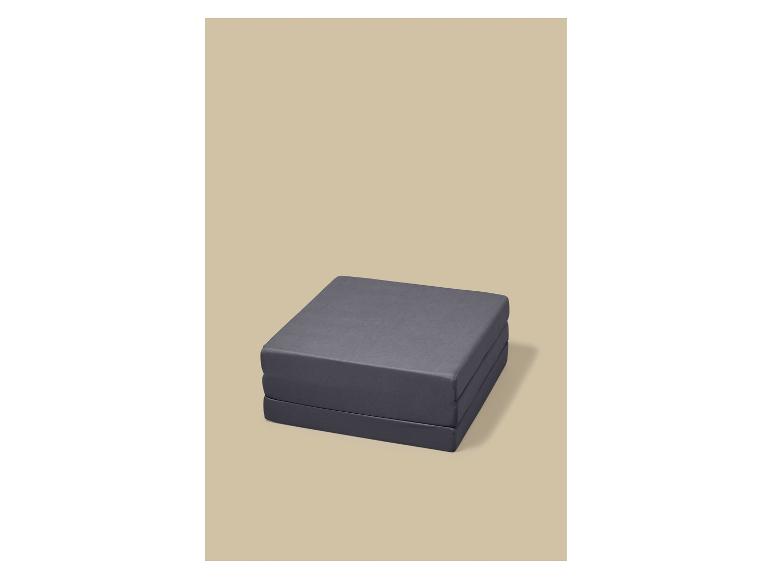 Matelas pliant gris sur fond beige.